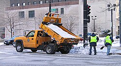 Workers spreading salt from a salt truck for deicing the road