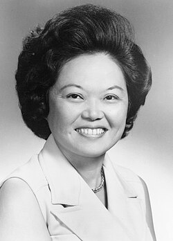 Photographic portrait of a smiling Asian woman in a sleeveless blouse
