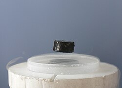 A magnet levitating over a superconducting material.