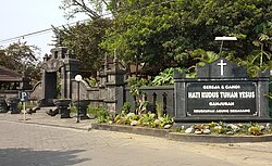 Indonesian word "Gereja" (Church) is derived from Portuguese "Igreja", while the word "kudus" (holy; sacred) is derived from Arabic "قدس (qudus)". The sign reads: "Gereja & Candi Hati Kudus Tuhan Yesus Ganjuran Keuskupan Agung Semarang" (The Church and Temple of the Sacred Heart of Jesus Ganjuran Archdiocese of Semarang).