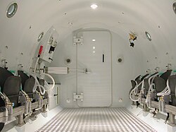 Internal view of a multiplace chamber for hyperbaric oxygen therapy, showing the airtight door leading to the entry lock.