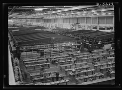 A small part of the world's largest one-story war production plant, the giant bomber factory at Willow Run, Michigan. Fixtures in background hold bomber wings during assembly, 1942.