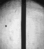 Very high-speed photography of a small projectile striking a thin aluminium plate at 7,000 m/s. The impact causes the projectile to disintegrate, and generates a large number of small fragments from the aluminium (spallation). This can occur without penetration of the plate.