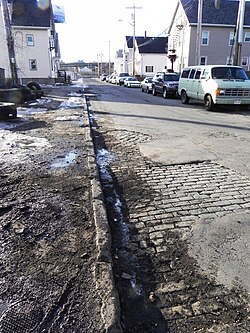 Setts visible beneath cracked asphalt in New Bedford, MA