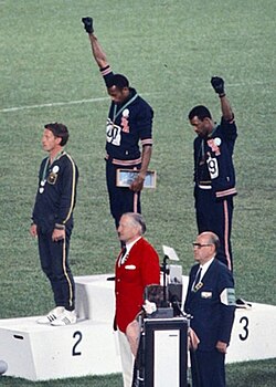 Puma-sponsored gold medalist Tommie Smith (center) and bronze medalist John Carlos (right) showing the raised fist at the 1968 Summer Olympics