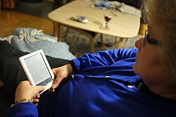 A woman reading a book using an e-reader