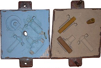 The cope and drag (top and bottom halves, respectively) of a sand mold, with cores in place on the drag.