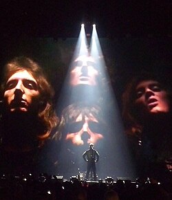 Robbie Williams, on stage in 2015 with the Queen image in the background, performed "We Are the Champions" for the 2001 medieval adventure film A Knight's Tale.