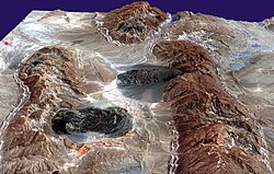 Satellite imagery of salt domes and salt glaciers, visible as darkish irregular patches, Zagros Mountains, southern Iran, near Karmowstaj. Gravity has caused the salt to flow like glaciers into adjacent valleys. The resulting tongue-shaped bodies are more than 5 kilometers long. The darker tones are due to clays brought up with the salt, as well as the probable accumulation of airborne dust.