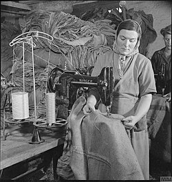 A woman using a machine to darn sacks.