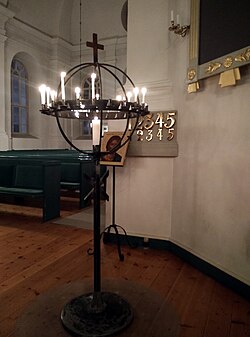 A votive candle rack stands before an icon of Christ Pantocrator in a Lutheran parish church of the Church of Sweden in Skellefteå.