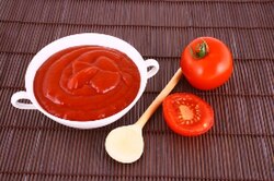 Tomato ketchup next to raw tomatoes