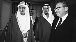 Kissinger and King Faisal of Saudi Arabia (left) in Riyadh on March 19, 1975. In the far background behind Faisal is his half-brother, the future King Fahd.