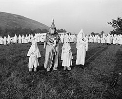 Two children wearing Ku Klux Klan robes and hoods stand on either side of Grand Dragon Samuel Green at Stone Mountain, Georgia, on July 24, 1948.