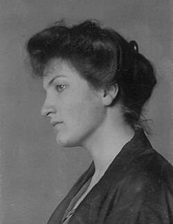 Head and shoulders photo portrait of an attractive dark-haired young woman looking left with a thoughtful expression