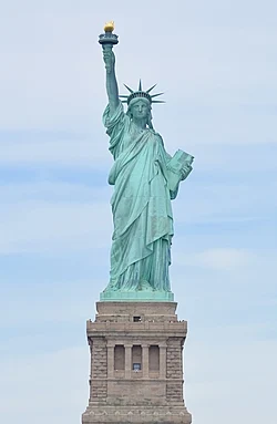 The Statue of Liberty, a large teal bronze sculpture on a stone pedestal