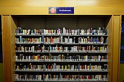 An audiobook collection in a library, containing a mix of cassette tape and CD-ROM formats