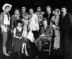 Guest stars for the 1961 premiere episode of The Dick Powell Show, "Who Killed Julie Greer?". Standing, from left: Ronald Reagan, Nick Adams, Lloyd Bridges, Mickey Rooney, Edgar Bergen, Jack Carson, Ralph Bellamy, Kay Thompson, Dean Jones. Seated, from left: Carolyn Jones and Dick Powell.