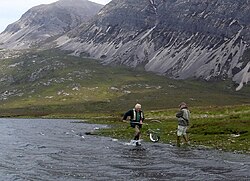 Angler and gillie landing a salmon in Scotland
