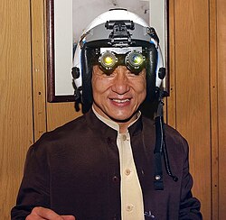 Jackie Chan tries on a fighter pilot's helmet with night vision goggles.