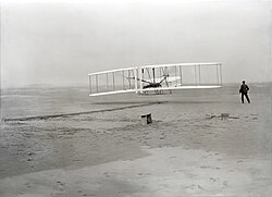 The Wright brothers' Wright Flyer making the first controlled, sustained flight of a powered airplane in 1903. Orville piloting while Wilbur observes