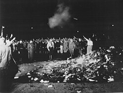 Thousands of books smoulder in a huge bonfire as Germans give the Nazi salute during the wave of book-burnings that spread throughout Nazi Germany.