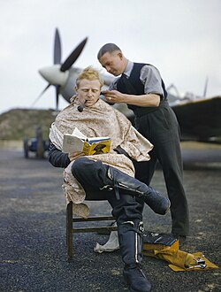 A pilot smoking a pipe while receiving a haircut, 1942
