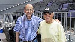 Two smiling, middle-aged men with arms around each other