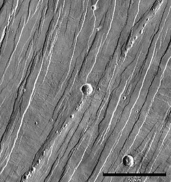 Simple graben and horsts in Tantalus Fossae on eastern flank of Alba Mons. Line of pit craters suggests drainage into subsurface voids, possibly created by tension cracks[50] (THEMIS IR daytime mosaic).