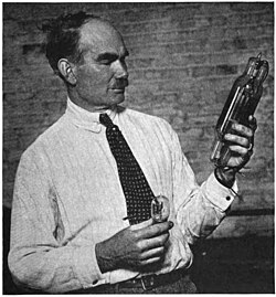 De Forest, some time between 1914 and 1922, with two of his Audions, a small 1-watt receiving tube (left), and a later 250-watt transmitting power tube (right), which he called an "oscillion".