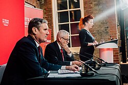 Keir Starmer and Jeremy Corbyn sitting on a panel in front of an audience, taken from an angel