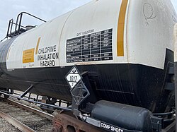 A railway tank car carrying chlorine, displaying hazardous materials information including a diamond-shaped U.S. DOT placard showing a UN number[87]