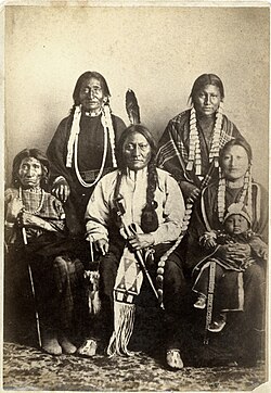 Sitting Bull and family 1881 at Fort Randall. Rear L–R: Good Feather Woman (sister), Walks Looking (daughter); Front L–R: Her Holy Door (mother), Sitting Bull, Many Horses (daughter) with her son, Courting a Woman