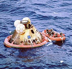 Columbia floats on the ocean as Navy divers assist in retrieving the astronauts.