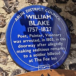 A blue memorial plaque on a wall outside of The Fox Inn at Felpham, West Sussex describing Blake's arrest. It reads "Arun District Council. William Blake 1757 - 1827. Poet, Painter, Visionary was arrested, in 1803, in this doorway after allegedly making seditious remarks to a soldier billeted at The Fox Inn.