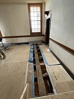 The same study during renovations in February 2025. The 18th century wooden structure of the mansion, with Roman numeral markings from the period, is exposed.