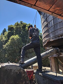 A fireman refills the water tank of a steam locomotive.