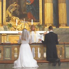 An Evangelical-Lutheran priest makes the sign of the cross, along with the bride and groom being wed, during a Nuptial Mass in the Church of Sweden