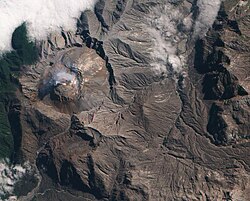 Satellite image of Chaitén volcano lava dome, Chile: The circular dome is brown and is surrounded by an ash covered landscape.