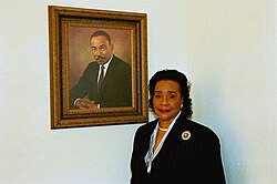 King poses next to a portrait of her husband in 2004