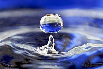 The formation of a spherical droplet of liquid water minimizes the surface area, which is the natural result of surface tension in liquids.