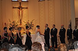 A couple exchange vows at the altar during a ceremony in a Catholic Church.
