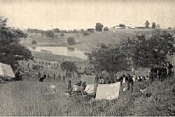 US Army encampment, 1st Volunteer Cavalry, Rough Riders, at the base of Kettle Hill about July 5, 1898. San Juan Hill and block houses are in background.