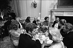 Photograph of First Lady Betty Ford, Prime Minister Harold Wilson of Great Britain, Happy Rockefeller, Cary Grant, Eileen Mehle, Van Cliburn, Mrs. Winston Guest, Danny Kaye, Margaret Truman Daniel, and British Secretary of State James Callaghan Seated in the State Dining Room during a State Dinner Honoring Prime Minister Wilson