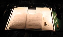 Conductor's score and batons on a lit, extra-large conductor's music stand