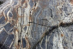 Erratic boulder of dark-colored amphibolite mingled with light-colored granitic bands, near the Trift Glacier, Switzerland