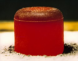 A pellet of 238PuO2 to be used in a radioisotope thermoelectric generator for either the Cassini or Galileo mission. The pellet produces 62 watts of heat and glows because of the heat generated by the radioactive decay (primarily α). Photo is taken after insulating the pellet under a graphite blanket for minutes and removing the blanket.