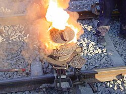 Thermite reaction proceeding in railway welding. Shortly after this, the liquid iron flows into the mould around the rail gap.