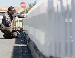 Man painting a fence