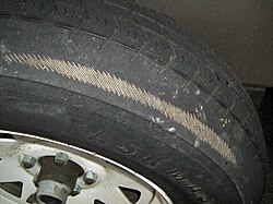Tire showing uneven tread wear to the point of exposing the casing